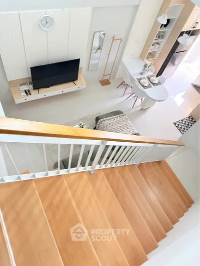 Modern open-plan living room with stylish decor and wooden staircase, perfect for contemporary living.
