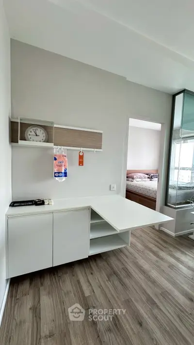 Modern apartment interior with sleek white furniture and wood flooring, featuring a cozy bedroom view.