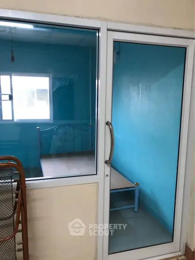 Compact bedroom with blue walls and glass sliding door
