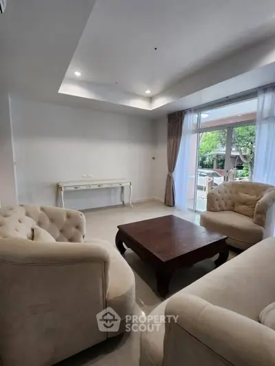 Elegant living room with plush seating and large windows offering natural light and garden view.