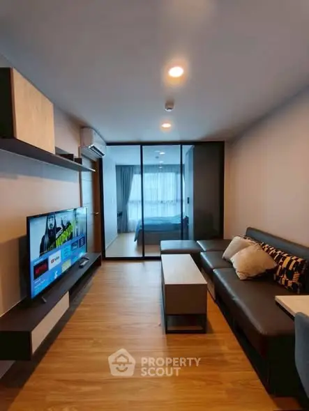 Modern living room with sleek furniture and TV, leading to a cozy bedroom.
