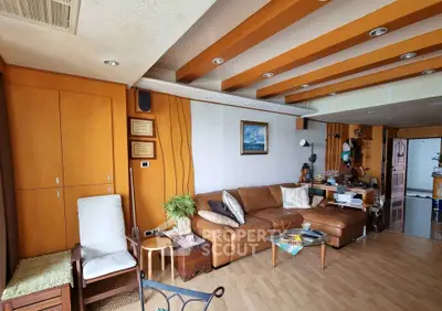 Spacious living room with modern design and wooden accents, featuring a cozy leather sofa and stylish decor.