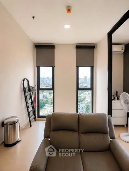 Modern living room with city view, featuring sleek furniture and large windows.