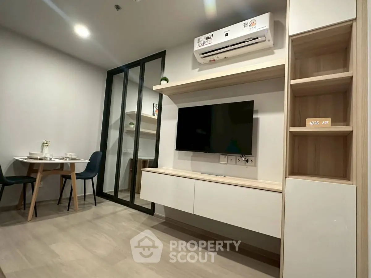 Modern living room with sleek TV setup and dining area in a stylish apartment.