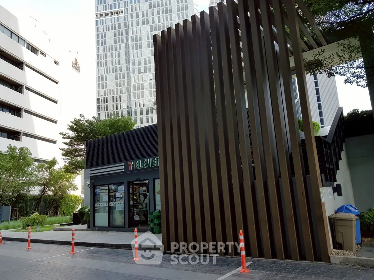 Modern urban building exterior with sleek design and greenery, featuring a convenience store entrance.