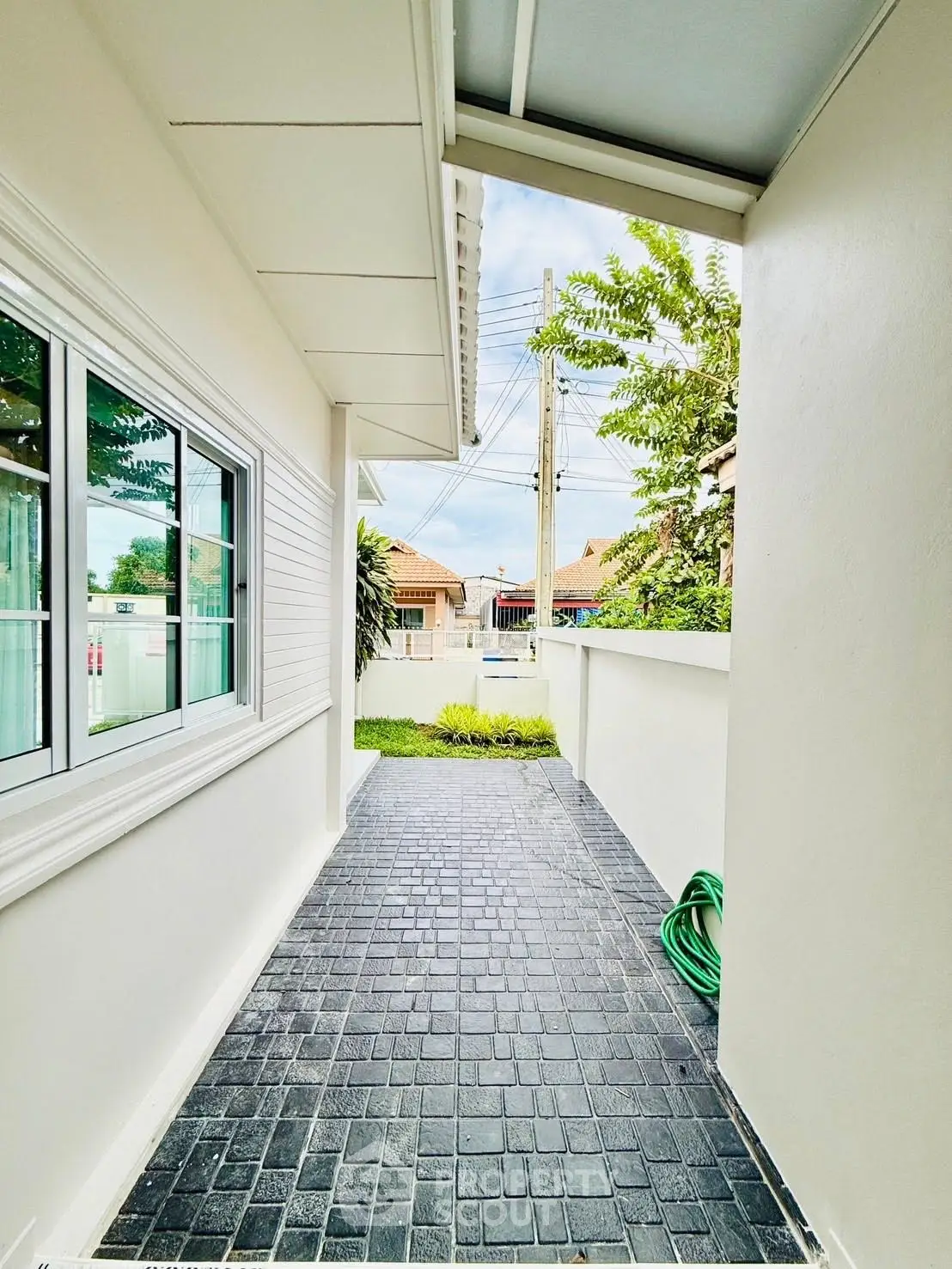 Charming exterior walkway with tiled path and lush greenery in a modern residential area.