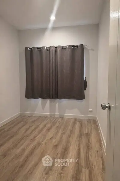 Spacious empty room with wooden flooring and window curtains, perfect for customization.