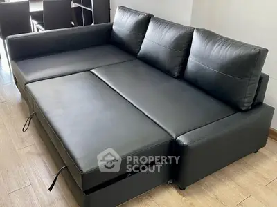 Modern black leather sofa bed in a stylish living room setting.