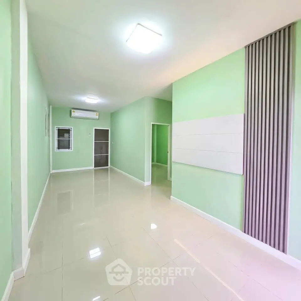 Spacious and bright interior with modern green walls and sleek tile flooring, perfect for versatile living space.