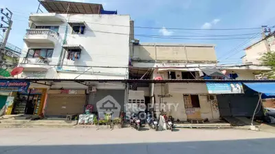 Street view of mixed-use building with shops and residential units, showcasing urban living and commercial potential.