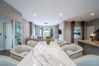 Spacious modern living room with elegant marble dining table and cozy seating area.