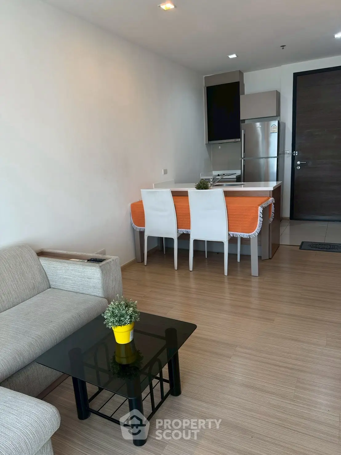 Modern open-plan living room with kitchen, featuring sleek furniture and stylish decor.