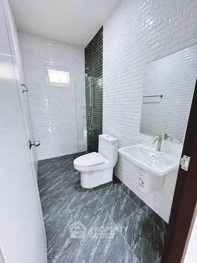 Modern bathroom with sleek design, featuring white brick tiles and a glass shower enclosure.