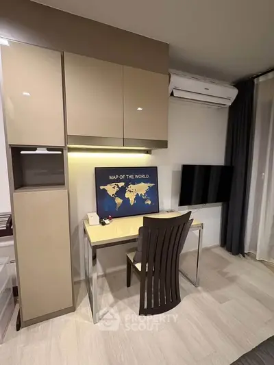 Modern study area with sleek desk, wall-mounted TV, and world map decor in stylish apartment.