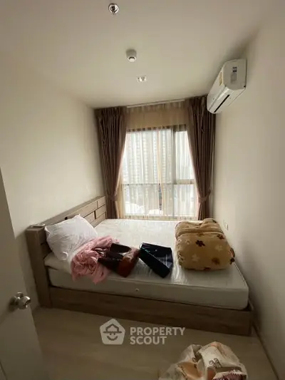 Cozy bedroom with large window and air conditioning in modern apartment.