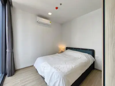 Modern bedroom with minimalist design and large window for natural light.