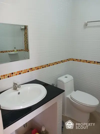 Modern bathroom with sleek sink and toilet, featuring stylish tile accents.