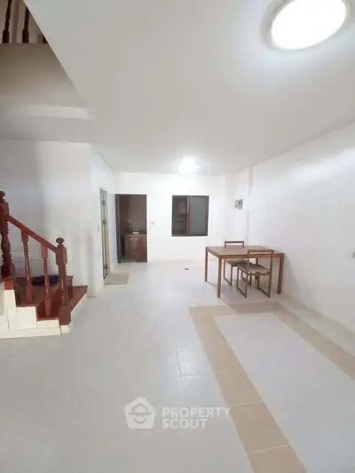 Spacious open-plan living area with staircase and dining set, ideal for modern living.