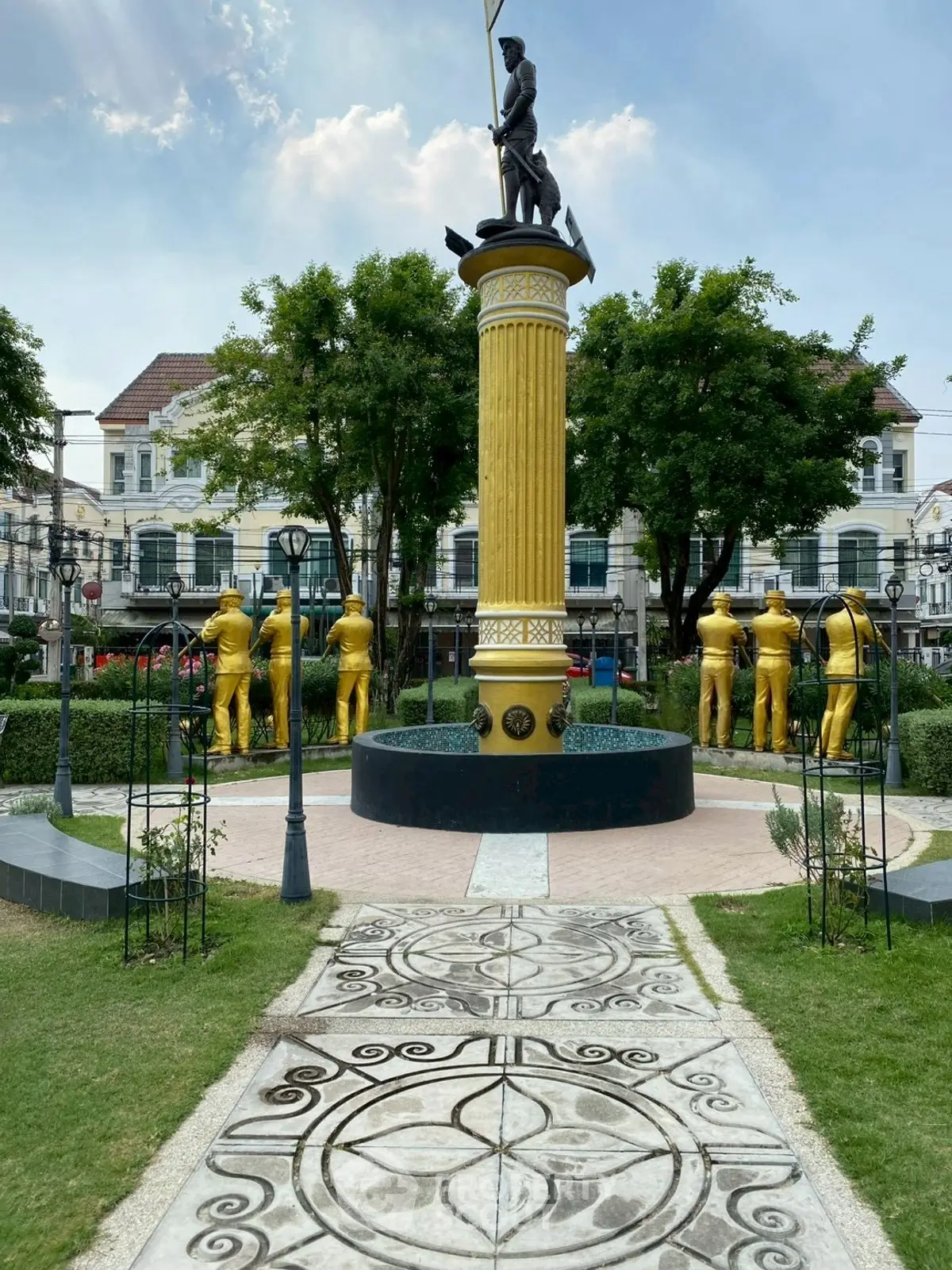 Elegant residential complex with a striking golden statue and lush landscaping.