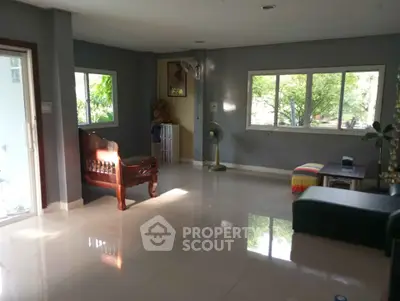 Spacious living room with large windows and elegant furniture, offering a serene view of lush greenery.
