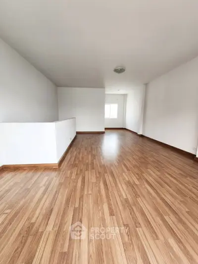 Spacious empty room with wooden flooring and white walls