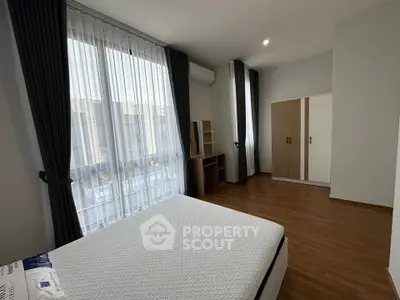 Spacious bedroom with large windows and modern furnishings in a stylish apartment.