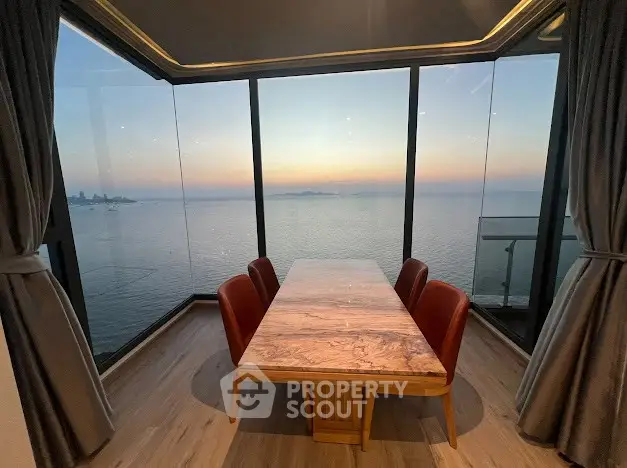 Stunning ocean view dining area with floor-to-ceiling windows and elegant marble table.