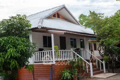 Charming single-story house with a cozy front porch and lush greenery, perfect for serene living.
