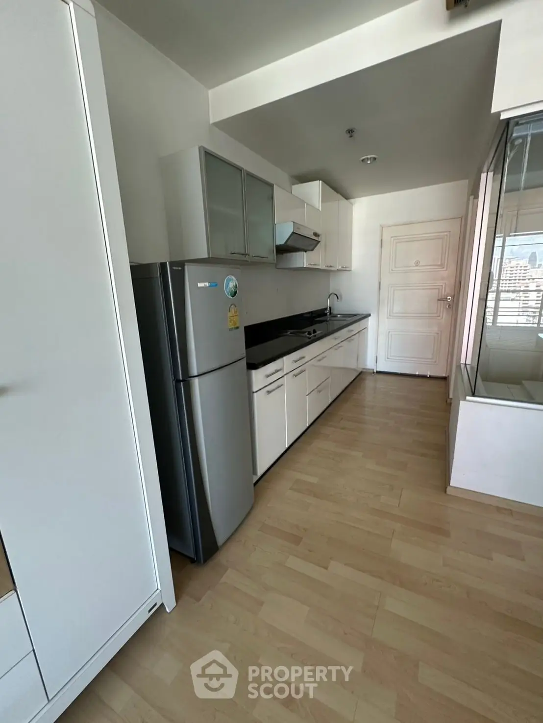 Modern kitchen with sleek cabinets and stainless steel fridge in a bright apartment.