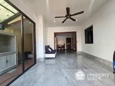 Spacious open-plan living area with marble flooring and ceiling fan, ideal for modern living.