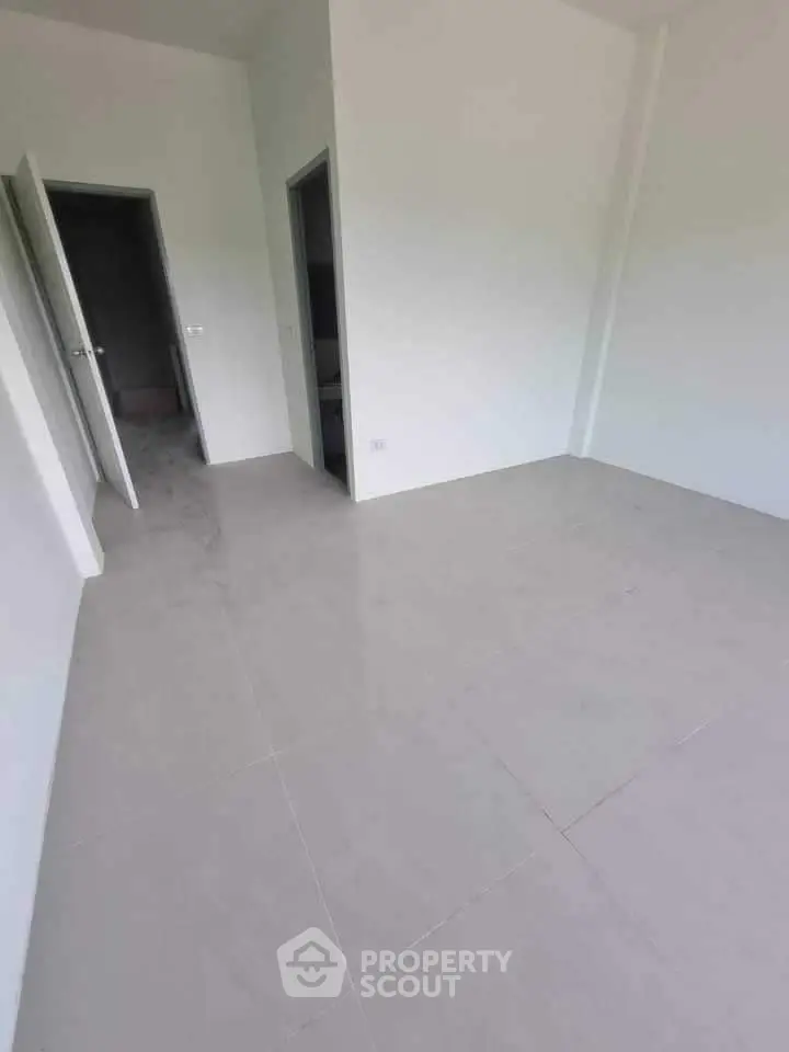 Spacious empty room with tiled flooring and open doors in modern apartment.