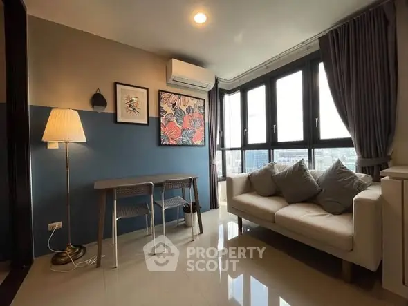 Modern living room with large windows and stylish decor in a high-rise apartment.