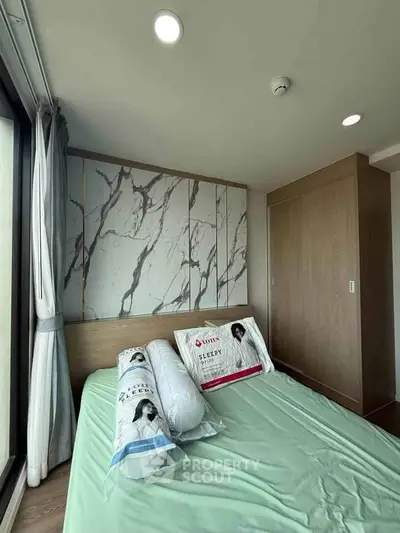 Modern bedroom with stylish marble accent wall and large window for natural light.