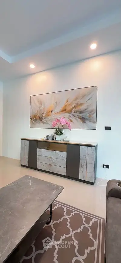 Modern living room with elegant decor and stylish furniture, featuring a large abstract painting and soft lighting.