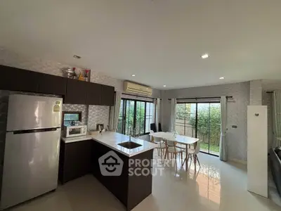 Modern kitchen and dining area with garden view, featuring sleek appliances and open layout.