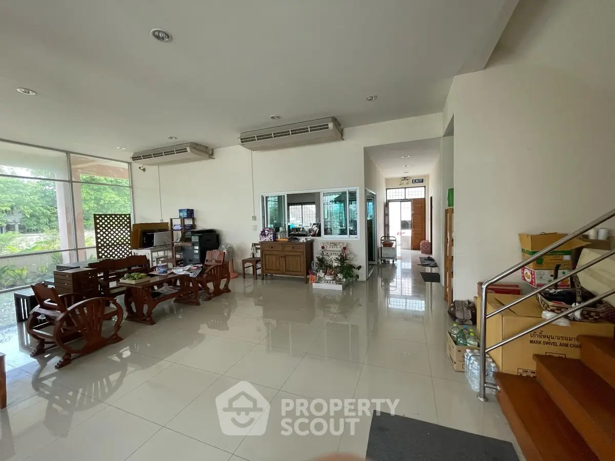 Spacious living room with wooden furniture and large windows offering garden views.