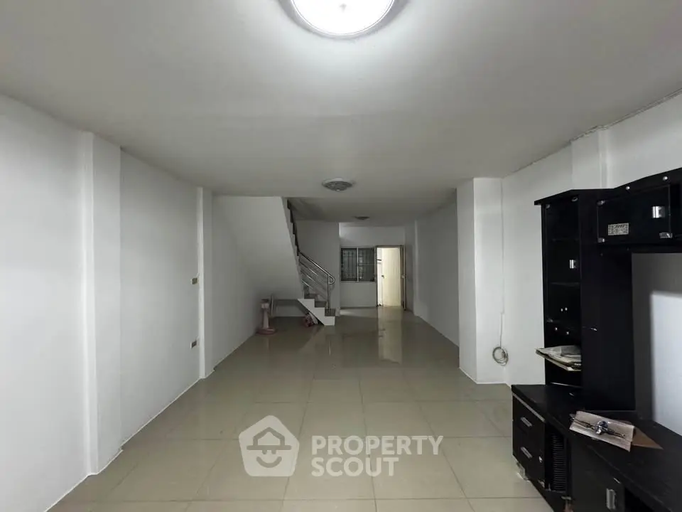Spacious open-plan living area with tiled flooring and modern staircase.