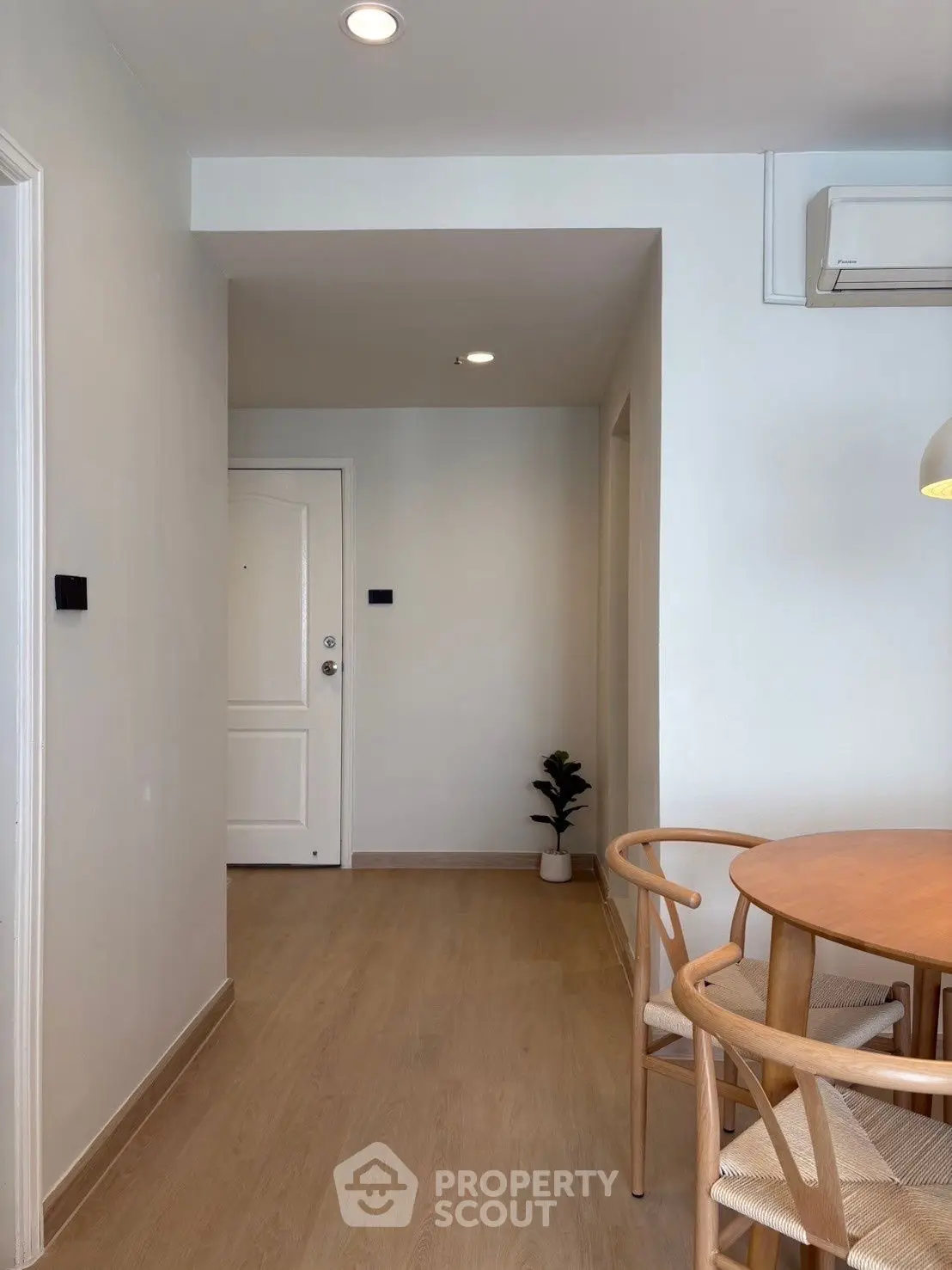 Cozy dining area with wooden table and chairs in modern apartment entryway.