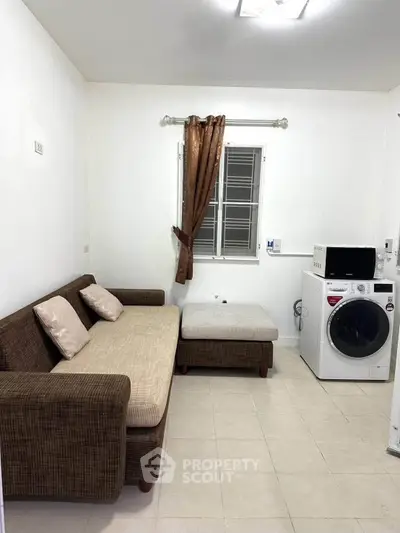 Cozy living room with sofa and washing machine, perfect for compact urban living.