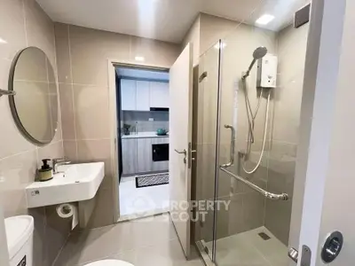 Modern bathroom with glass shower and sleek fixtures in contemporary apartment.