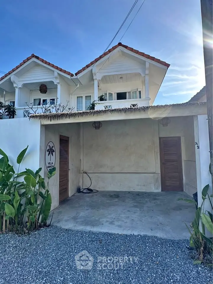 Charming villa entrance with rustic garage and lush greenery, perfect for serene living.