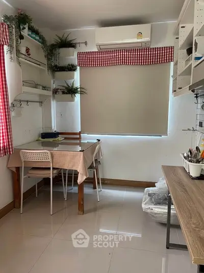 Cozy kitchen with dining area, featuring red checkered curtains and modern air conditioning unit.
