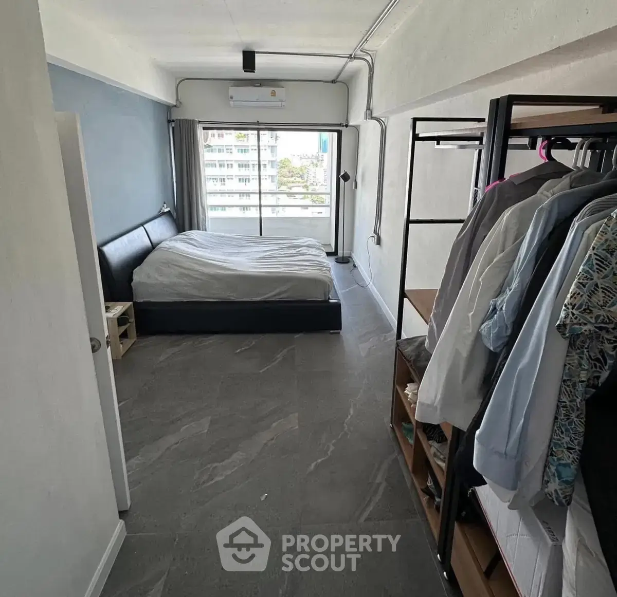 Modern bedroom with sleek design and ample natural light, featuring a stylish bed and open wardrobe.