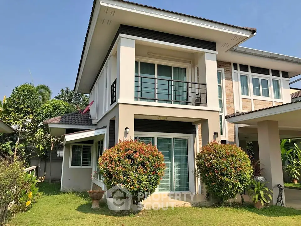 Modern two-story house with lush garden and balcony in a serene neighborhood.