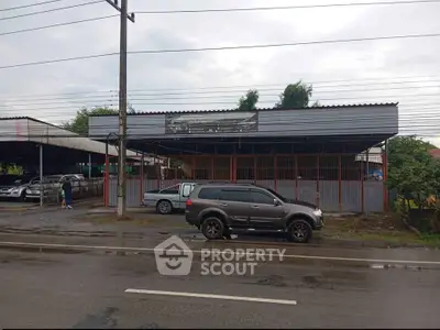 Commercial property with ample parking space on a rainy day, ideal for automotive business.