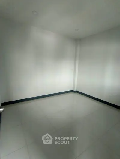 Spacious empty room with white walls and tiled floor, perfect for customization.