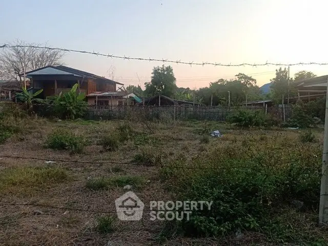 Spacious vacant land with potential for development, surrounded by greenery and residential homes.