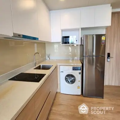 Modern kitchen with sleek white cabinetry, stainless steel appliances, and a convenient washing machine, perfect for urban living.