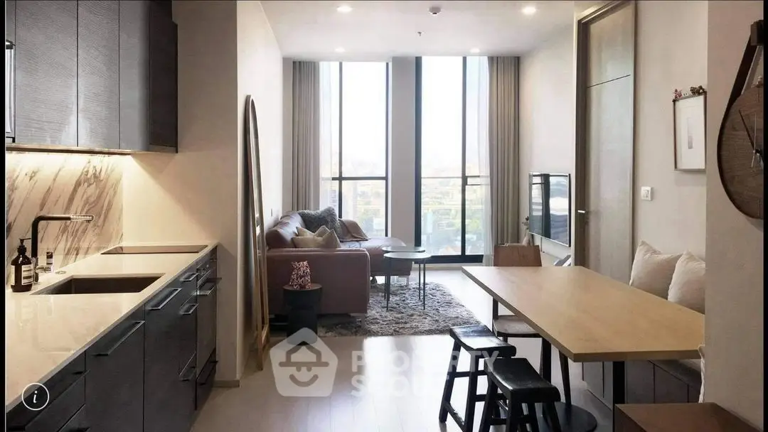 Modern living room with open kitchen, stylish decor, and large windows offering a stunning view.