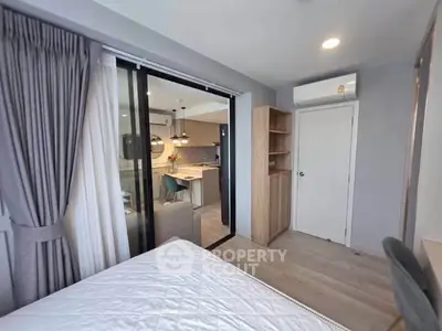 Modern bedroom with sliding glass doors leading to a stylish kitchen, featuring elegant lighting and contemporary design.